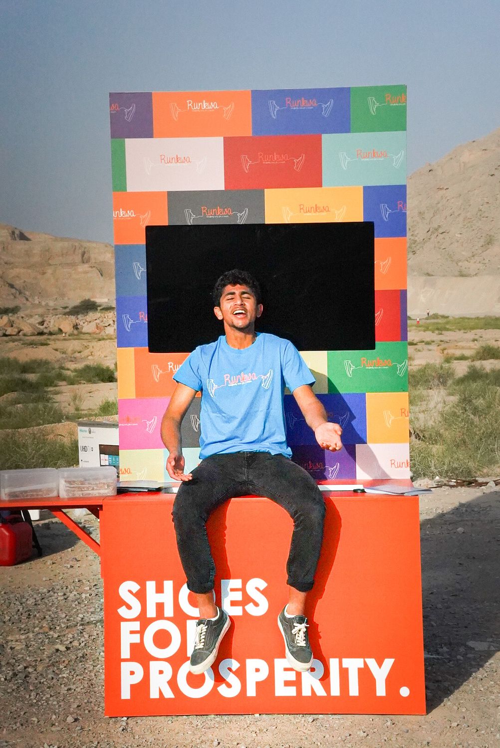 Zach sitting on the Shoes for Prosperity collection booth