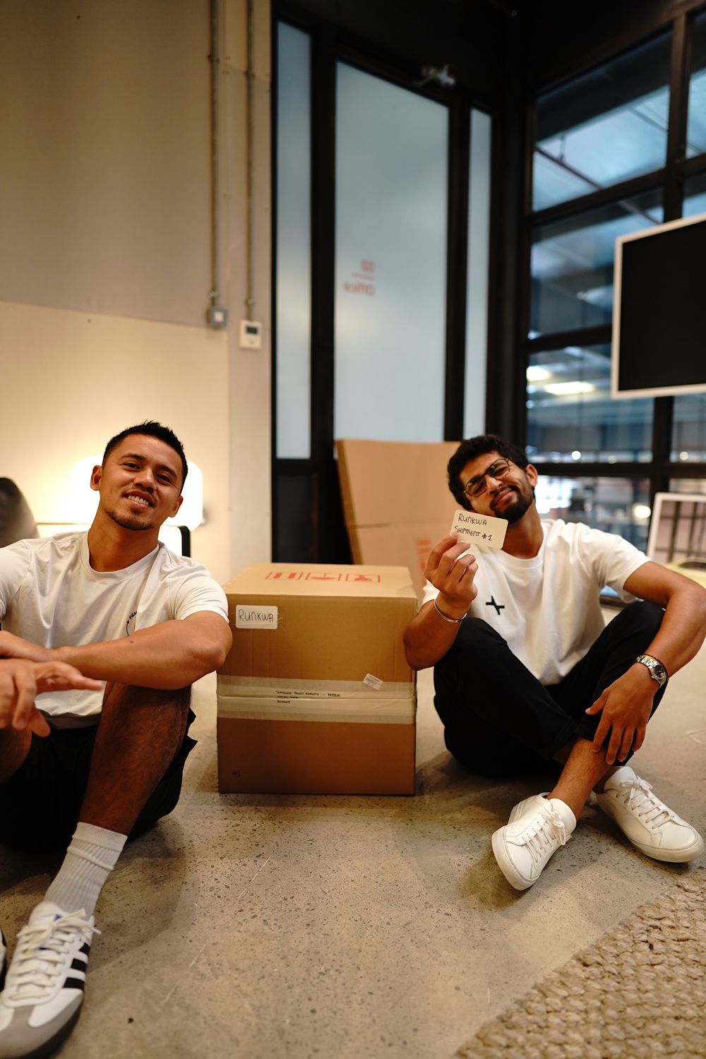 Zach and Kirk sitting by a box of RunKwa shoes