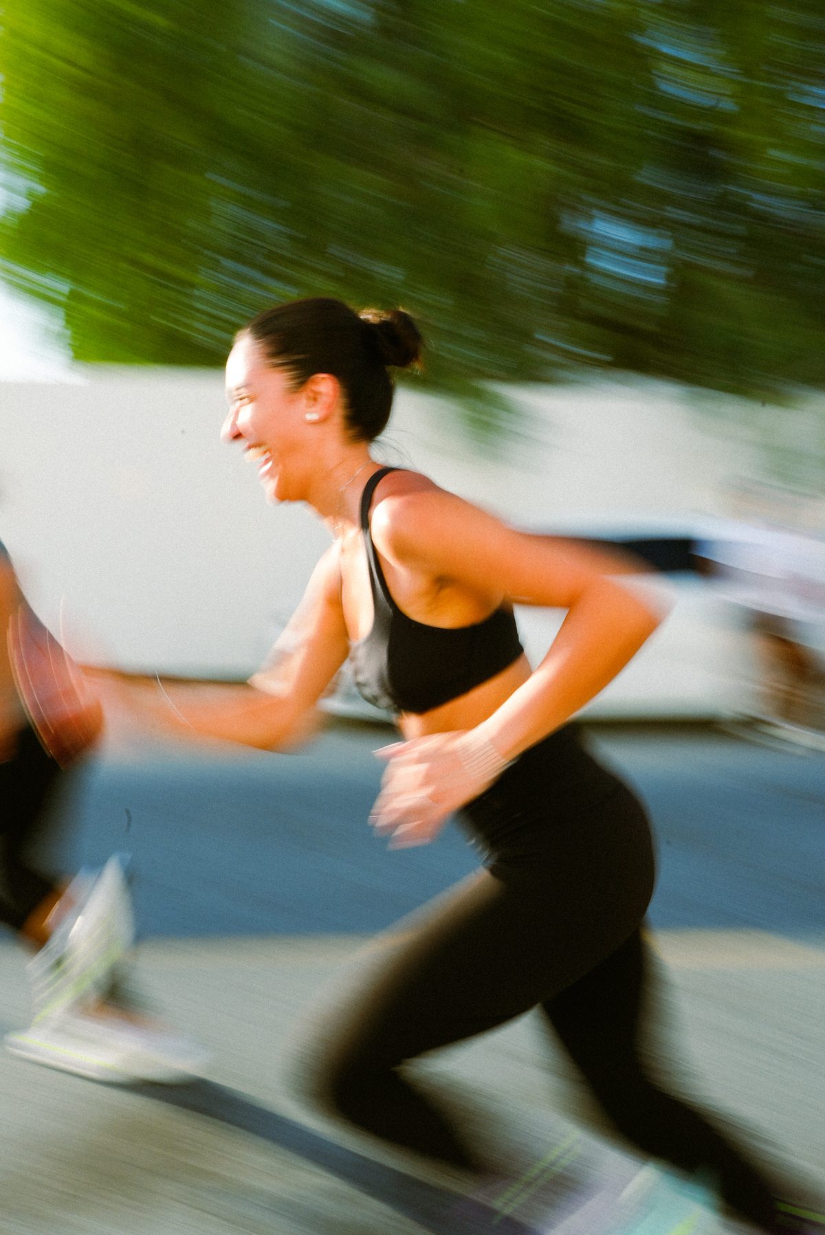 A runner laughing mid-stride on a sunny run
