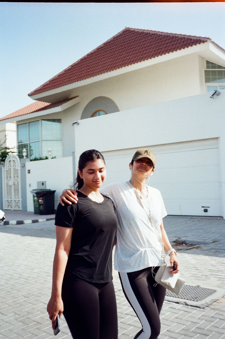 Two runners walking arm in arm past a villa after the run