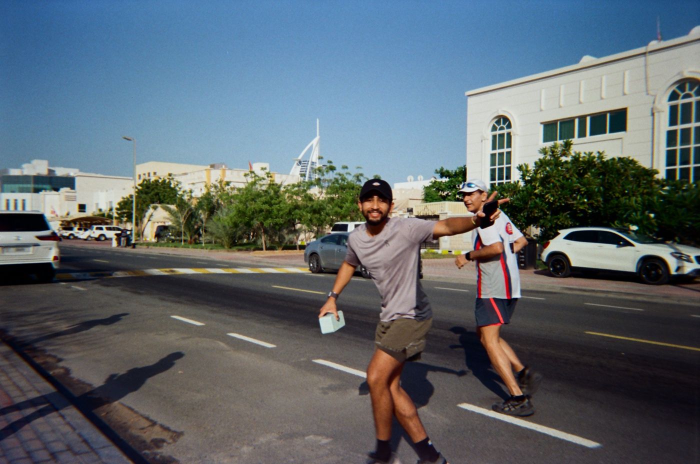 A runner pointing at the camera mid-run, with the Burj Al Arab behind