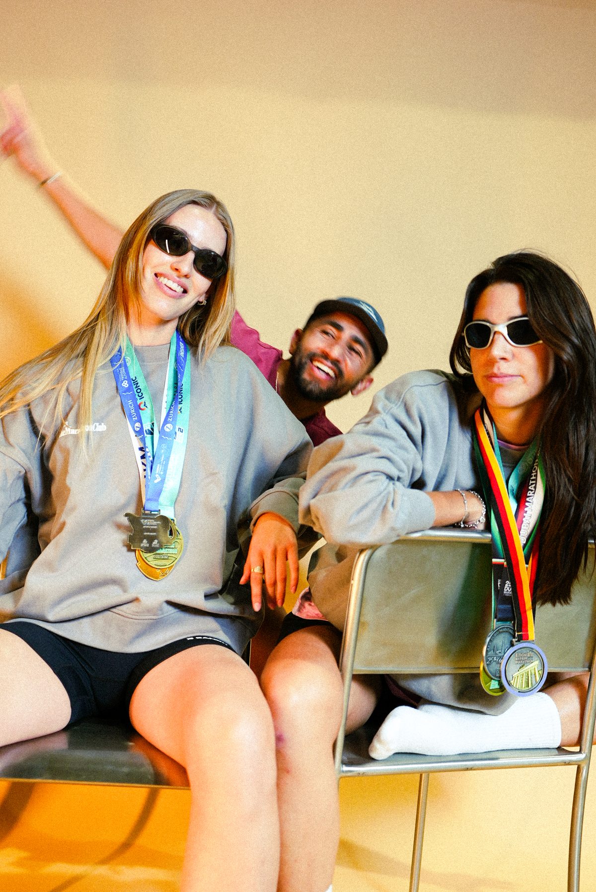 Three TheMarathonClub members laughing in sweatshirts and marathon medals