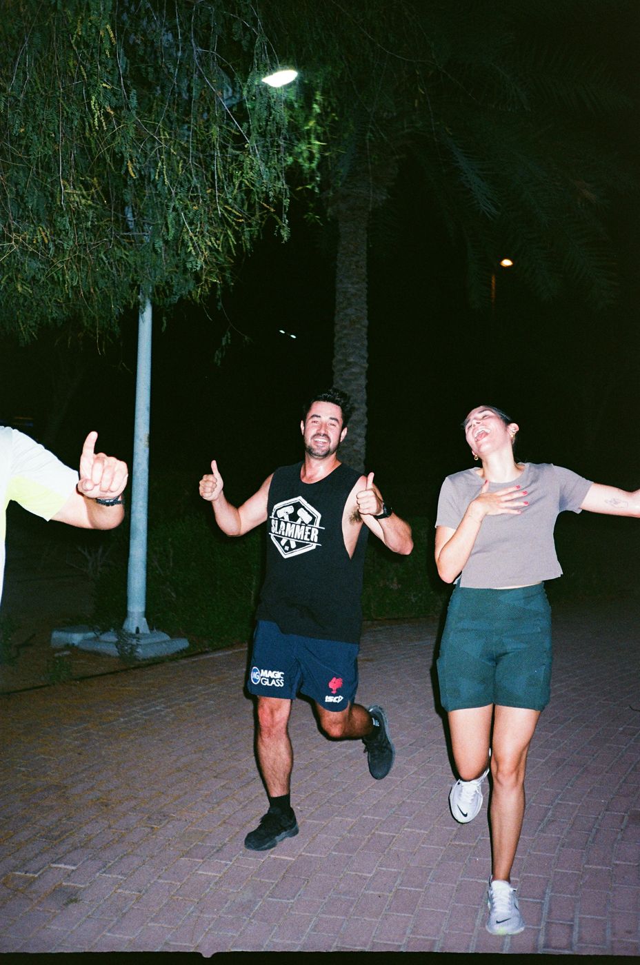 Two runners laughing and giving thumbs up on a night run